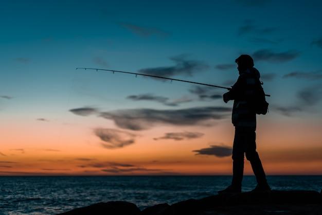 Free photo silhouette of person fishing in sea