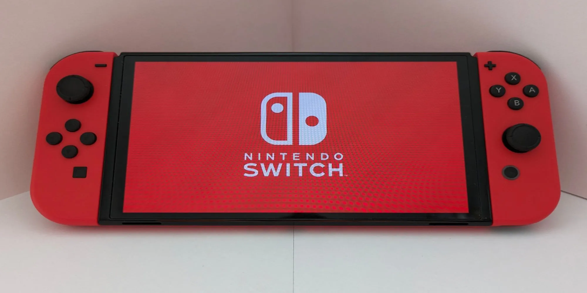 Máy console Nintendo Switch màu đỏ tựa vào tường trắng, biểu tượng cho nền tảng vẫn được Nintendo hỗ trợ game mới